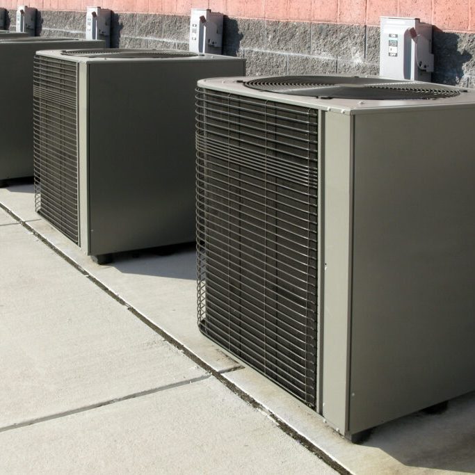 Row of commercial HVAC air conditioner outside condenser units outside a commercial building as part of a climate control cooling and refrigeration conditioning system